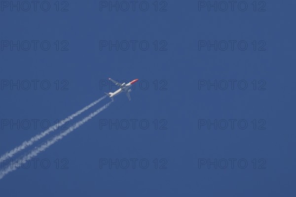 Boeing 737 jet passenger aircraft of Norwegian Air airlines flying in a blue sky with contrails or vapour trails behind, England, United Kingdom