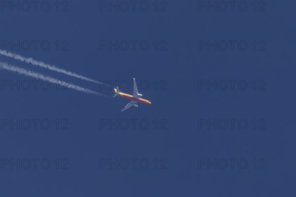 Boeing 767 jet cargo aircraft of DHL airlines flying in a blue sky with contrails or vapours trails behind, England, United Kingdom