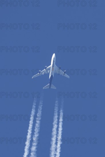 Boeing 747 jumbo jet cargo aircraft of Atlas air airlines flying in a blue sky with contrails or vapour trails behind, England, United Kingdom