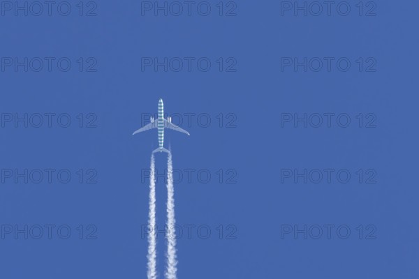 Boeing jet passenger aircraft flying in a blue sky with contrails or vapour trails behind, England, United Kingdom