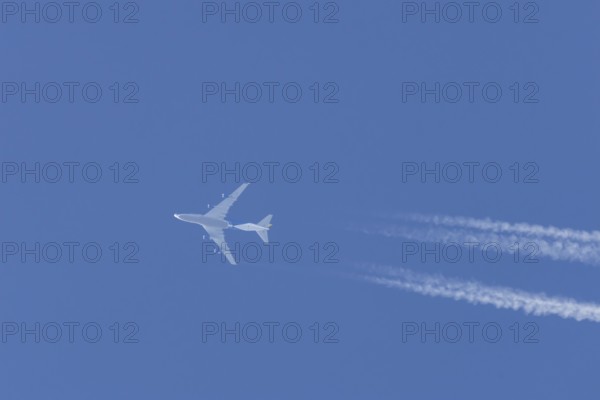 Boeing 747 jumbo jet cargo aircraft flying in a blue sky with contrails or vapour trails behind, England, United Kingdom