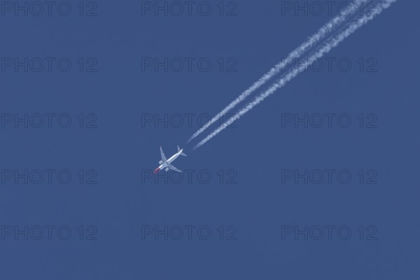 Boeing 737 jet passenger aircraft of Norwegian Air airlines flying in a blue sky with contrails or vapour trails behind, England, United Kingdom