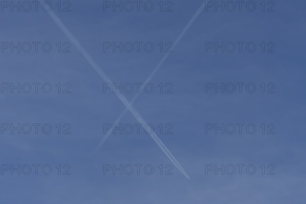 Aircraft contrails or vapour trails crossing in a blue sky, England, United Kingdom