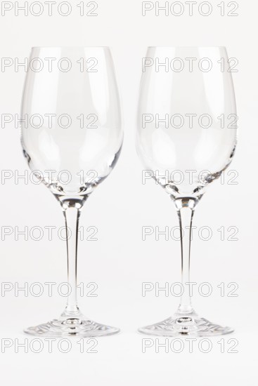Two elegant, transparent wine glasses with long stems next to each other