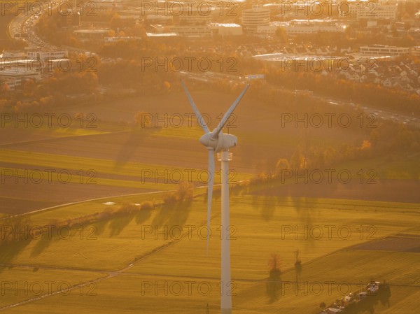 Close-up of a wind turbine standing over fields in the evening sun, Grüner Heiner, Korntal, Germany