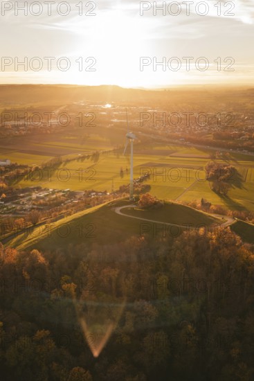 A wind turbine overlooks a vast, autumnal landscape at sunset, Grüner Heiner, Korntal, Germany