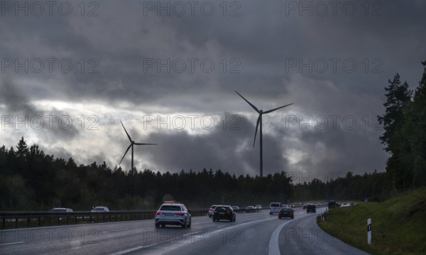 Tourist traffic on the A9 motorway during thunderstorms, wind turbines in the pine forest in the back, Bavarian Forest, Bavaria, Germany