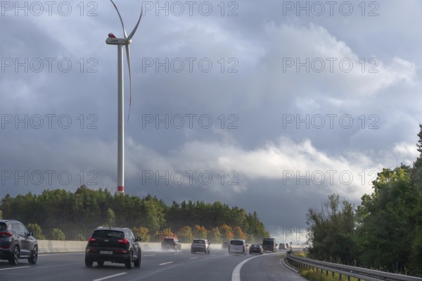 Tourist traffic on the A9 motorway during thunderstorms, a wind turbine in the back, Bavarian Forest, Bavaria, Germany