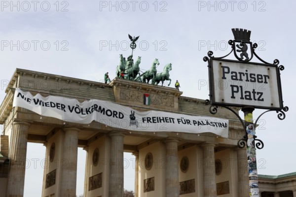 Several activists drop a banner with the inscription Never again genocide, freedom for Palestine and the Palestinian flag and set off pyrotechnics at the Brandenburg Gate, Berlin, 13.11.2025