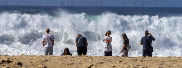 Tourists watch the waves of the Atlantic on the rocky plateau of Sito, also known as Forte São Miguel, a surfing paradise with monster waves in the months of November to February, Nazaré, Portugal