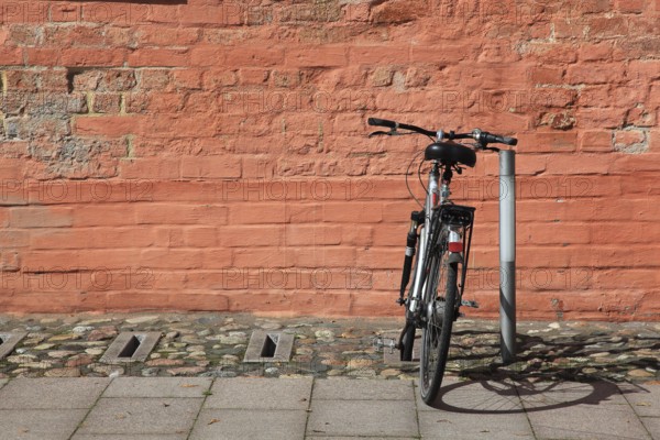 Bicycle parked in front of a red brick wall