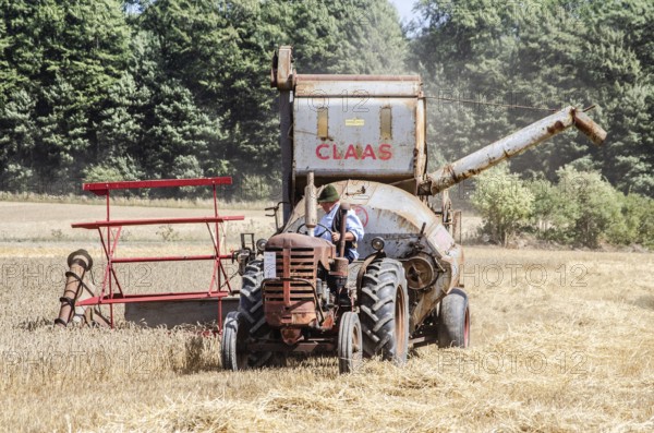 Older tractor-drawn Claas combine harvester harvesting wheat at old-fashioned harvest festival in Svenstorp, Ystad municipality, Skåne county, Sweden, Scandinavia