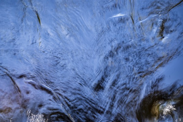 Shimmering blue water surface of a stream, current, light reflections, abstraction, long exposure, Sweden