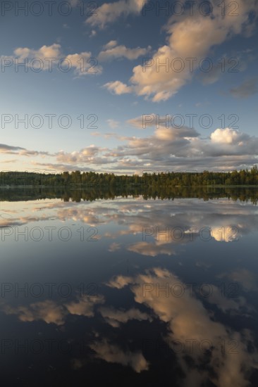 Clouds reflected on the water surface, forest lake, evening mood, at Sunne, Sweden
