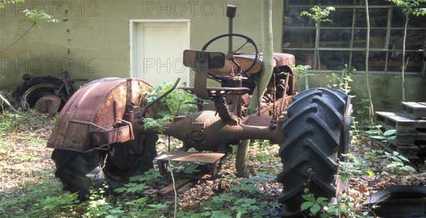 Rusted tractor at a car cemetery in a forest, Marksboro, New Jersey, USA