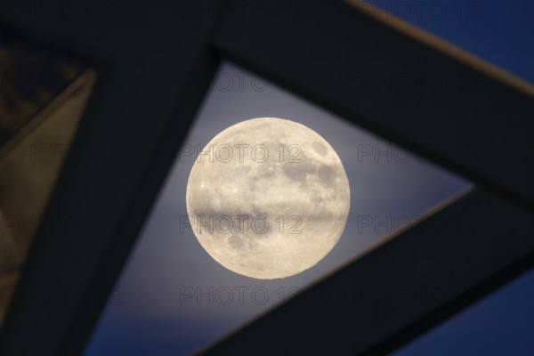 The full moon sweeps along the Frankfurt evening sky and passes the pillars of the rafter bridge, Frankfurt am Main, Hesse, Germany
