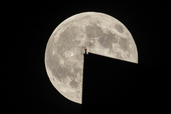 The full moon sweeps along the Frankfurt evening sky and passes the tip of the European Central Bank (ECB), making it look like a huge video game Pacman figure to the viewer, Frankfurt am Main, Hesse, Germany
