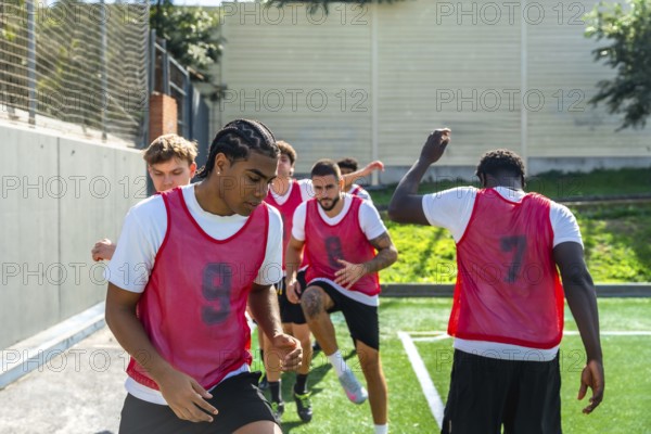 Group of diverse male soccer players engaging in intense drills and warm up exercises on an artificial turf field, focusing on teamwork and athletic performance during practice