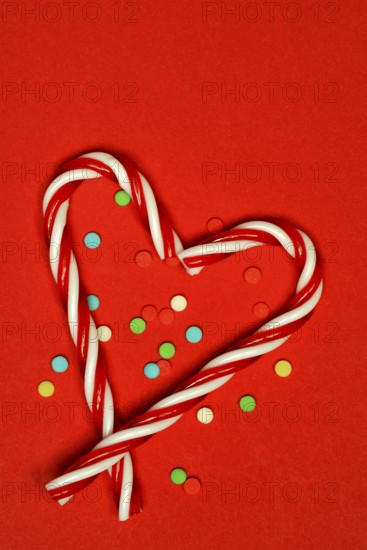 Candy canes and sugar confetti against red background, Christmas