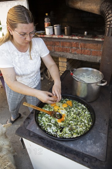 Serbian woman cooking przeno or traditional Serbian dish in her kitchen, Vrmdza, Sokobanja, Serbia