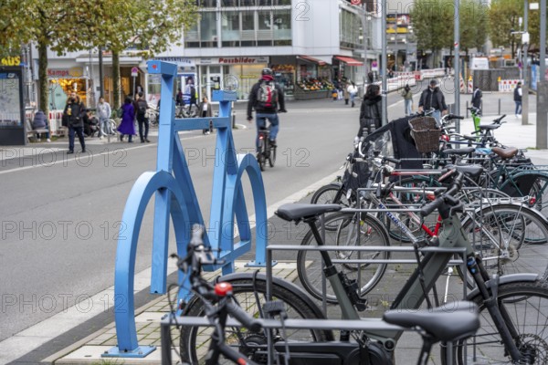 Bicycle parking spaces, with so-called leaning bars and a large blue bicycle silhouette, to make parking spaces visible at Bochum City Hall, North Rhine-Westphalia, Germany