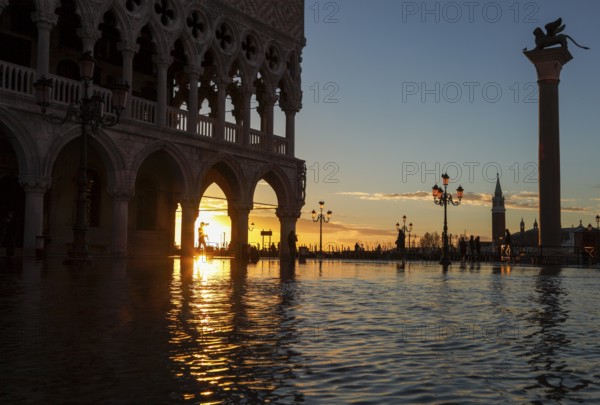 View through the arcades of the Doge's Palace at sunrise on Piazzetta during Acqua Alta, Venice, Veneto, Italy