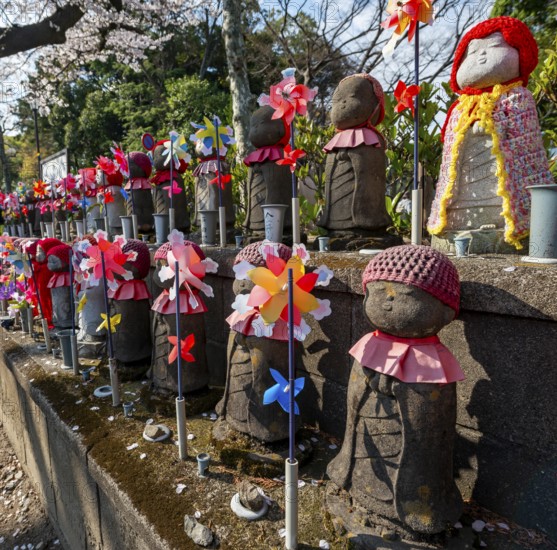 Jizo statues with red crocheted caps, guardian deities for deceased children, Unborn Children Garden, Zojoji temple, Buddhist temple complex, cherry blossom, Tokyo, Japan