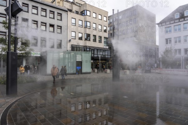 Digital water feature, Blue Cloud water installation on Husemanplatz in downtown Bochum, water mist is sprayed from 4 metal masts, which, in conjunction with the circular water surface, is intended to cool the surrounding area when it is hot, colored light images are projected into the water mist via projectors, part of the transformation of Husemanplatz
