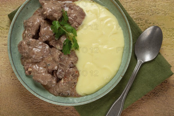 Liver beef stroganoff with mashed potatoes, table setting in green tones, homemade