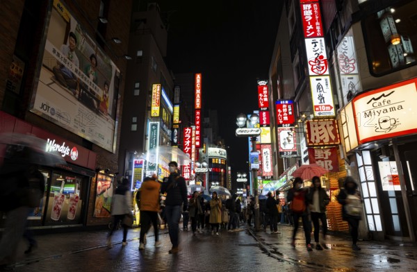 Busy pedestrian zone with many shopping centers and stores, illuminated with lots of neon signs at night, Shibuya, Udagawacho, Tokyo, Japan