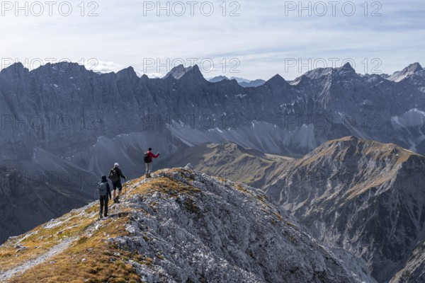 Hikers on the summit ridge of the Gamsjoch, behind rock faces of the Laliderer Spitze, eastern Karwendel, Tyrol, Austria
