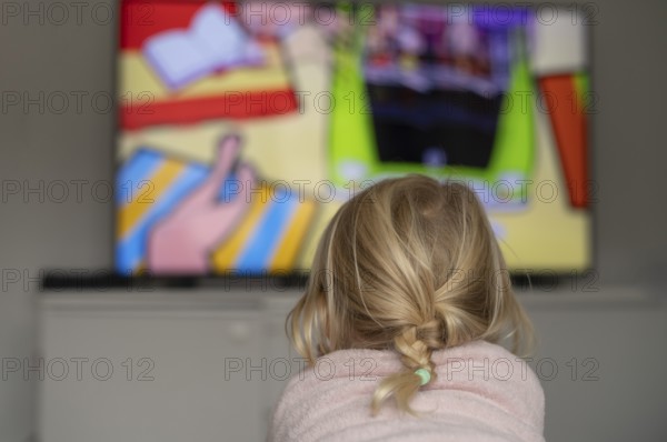Child, girl, 4 years old, blonde, lying on sofa, watching TV, watching television, in front of television, from behind, braid, monitor, children's program, children's program, children's television, colorful, Stuttgart, Baden-Württemberg, Germany