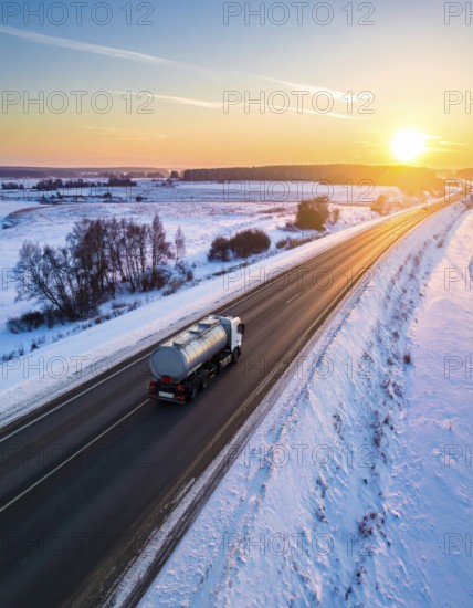 Petrol cargo truck lorry tanker driving on highway hauling oil products at sunrise, wide snowy landscape in winter, AI generated