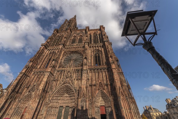 Strasbourg's Notre Dame Cathedral stands majestically there. Its magnificent architectural details are clearly visible under the blue, cloudy sky. Bas Rhin, Alsace, France