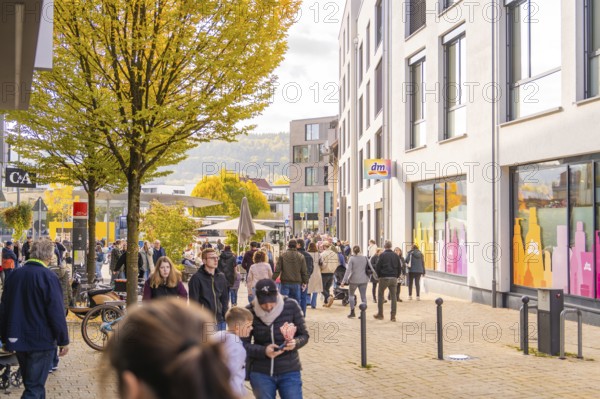 Busy shopping street in autumn, people strolling between modern buildings and colorful shops, Urschelherbst street festival, Nagold, Germany