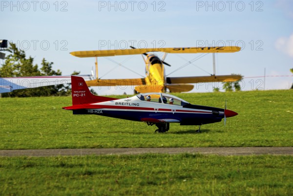 An RC model of a Pilatus PC-21 with advertising for the Swiss watch brand Breitling during a flight demonstration as part of an air show at the Rossfeld in Metzingen-Glems, Baden-Württemberg, Germany, for editorial use only