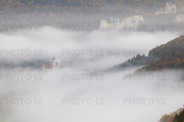 View of Benedictine monastery Beuron, Archabbey of St. Martin, limestone rock, rock face, mixed forest, autumn colours, fog, autumn, Fridingen, Danube Valley, Upper Danube nature park Park, Baden-Württemberg, Germany