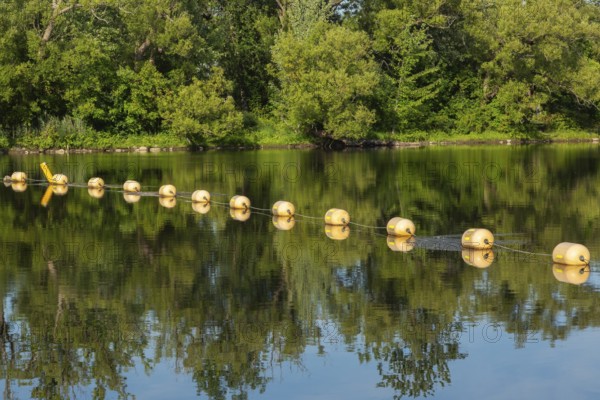 String of yellow cautionary navigation marker buoys on water surafce of river serving to warn, signal or indicate of a hazard beyond, Terrebonne, Quebec, Canada