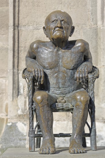 Sculpture The Old Man by Guido Messer 1981 bronze sculpture, modern art, old naked sitting man with angry facial expression, male figure, naked, angry, grumpy, bad-tempered, emotion, town church, Balingen, Swabian Alb, Baden-Württemberg, Germany