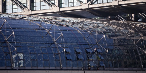 Three male glass cleaners cleaning a glass roof at Berlin Central Station, Berlin, Germany