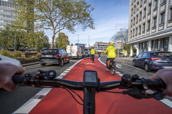 Riding a bike in a bike lane, marked in red to attract the attention of motorists, between 2 lanes, Huyssenallee, in front of Europaplatz, in the city centre of Essen, North Rhine-Westphalia, Germany