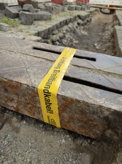 Flapping tape with the indication of an installed fibre optic cable at a construction site in Wuppertal, Germany