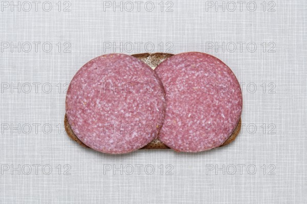 Top shot of a slice of bread smeared with margarine and topped with salami on a white Resopal plate