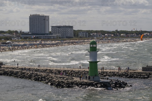 Green and white lighthouse, pier light Westmole in front of lively beach and hotels in the background, waves, Warnemünde, Rostock, Mecklenburg-Western Pomerania, Germany