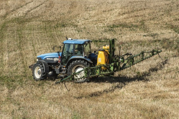 Tractor spreading fertilizer on harvested stubble field in Ystad municipality, Skåne county, Sweden, Scandinavia