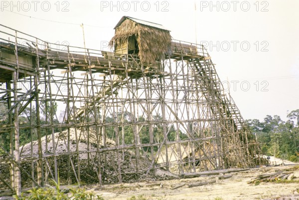Open Cast gravel-pumping tin mine Malaya, Malaysia, south east Asia 1964 - pumping raises the slurry from the sump to an elevated wooden sluice level called a palong