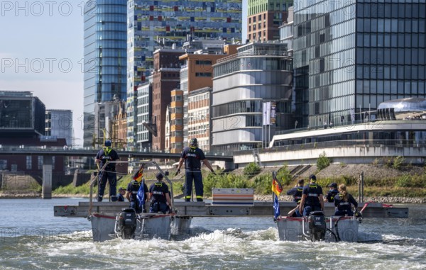 Exercise run of a multi-purpose pontoon on the Rhine, Medienhafen, the skipper gives instructions to the two helmsmen by hand signal, the specialist group for water hazards, in Düsseldorf, the motorised pontoon can be used as a ferry for people or equipment, as a working platform or bridge, during the major exercise FÜLEX25, lasting several days, of the THW, Technisches Hilfswerk, Landesverband North Rhine-Westphalia, over 3500 volunteers from the 127 North Rhine-Westphalia local associations practise many different scenarios over 4 weekends