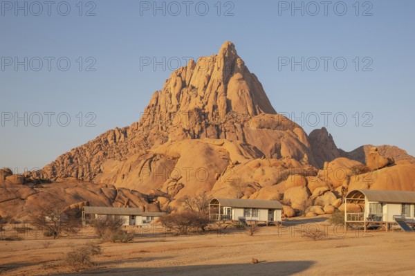 The isolated Spitzkoppe mountain (1728 m) provides a dramatic backdrop for the chalets of the upmarket Spitzkoppen Lodge. Damaraland, Namibia