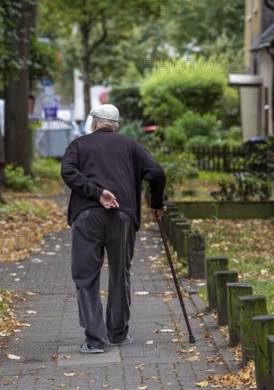 Elderly man going for a walk with the help of a walking stick, North Rhine-Westphalia, Germany