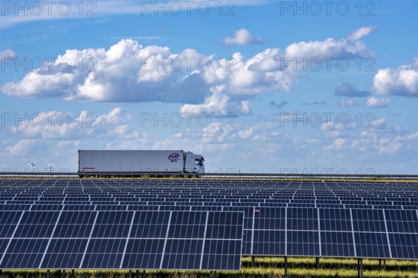 86, 5 MW peak ground-mounted photovoltaic systems, by RWE, with over 141, 000 solar modules, on a verge, over 1 km long, along the A44 motorway near Bedburg, at the Jackerath junction, recultivated open-cast mining site, field with sunflowers, North Rhine-Westphalia, Germany